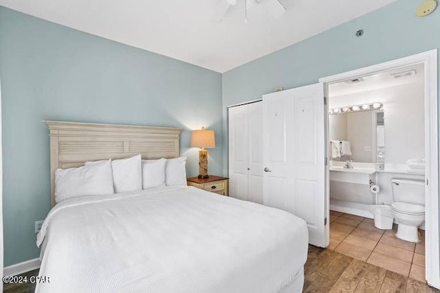 bedroom featuring light wood-type flooring, connected bathroom, ceiling fan, and a closet