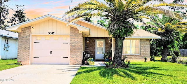 view of front of home with a lawn, driveway, an attached garage, and brick siding
