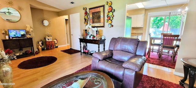 living area with visible vents, lofted ceiling, and wood finished floors