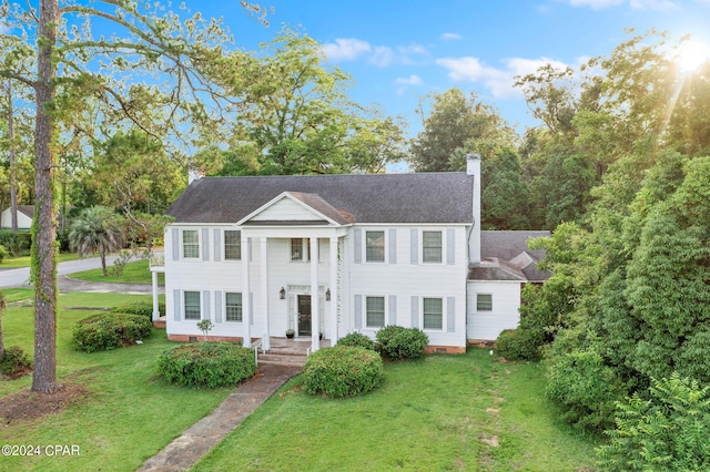 view of front facade featuring a front yard, roof with shingles, crawl space, and a chimney