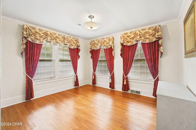 unfurnished room with hardwood / wood-style flooring, ornamental molding, and visible vents