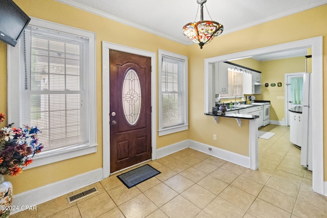 entrance foyer with light tile patterned flooring, sink, crown molding, and an inviting chandelier