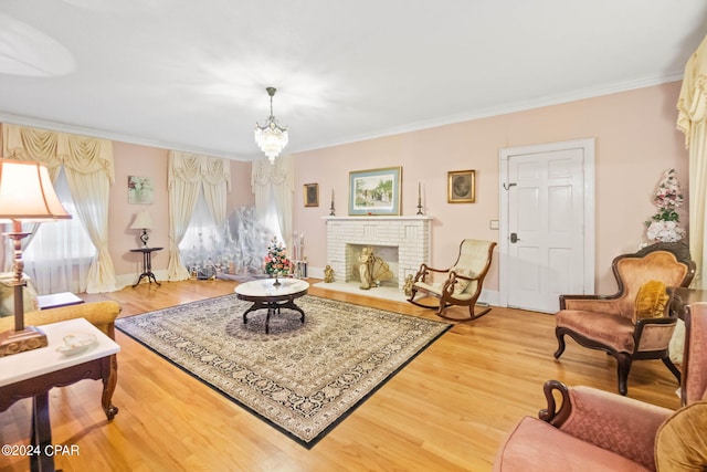 living room featuring a brick fireplace, hardwood / wood-style flooring, ornamental molding, and an inviting chandelier