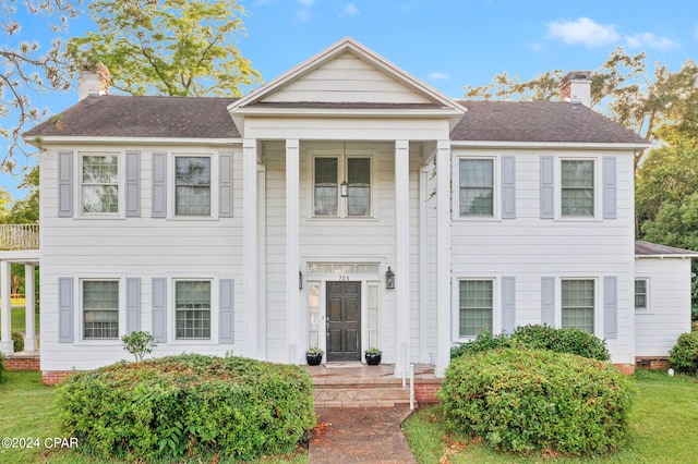greek revival house with a shingled roof and a chimney