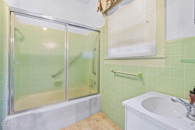 bathroom with tile patterned flooring, tile walls, and combined bath / shower with glass door