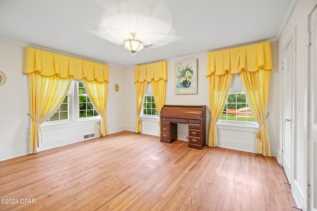 unfurnished living room featuring hardwood / wood-style flooring, a healthy amount of sunlight, and crown molding