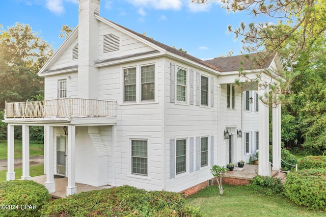 back of house with a yard and a balcony