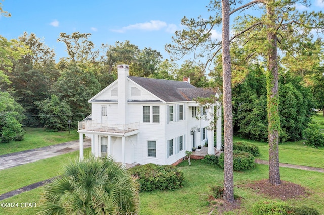 view of home's exterior with a lawn, a chimney, and a balcony