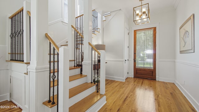 foyer featuring light wood-type flooring, an inviting chandelier, and ornamental molding