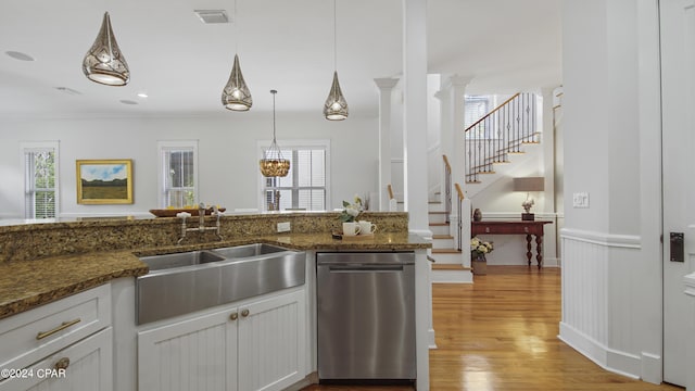 kitchen featuring decorative columns, stainless steel dishwasher, pendant lighting, and white cabinets