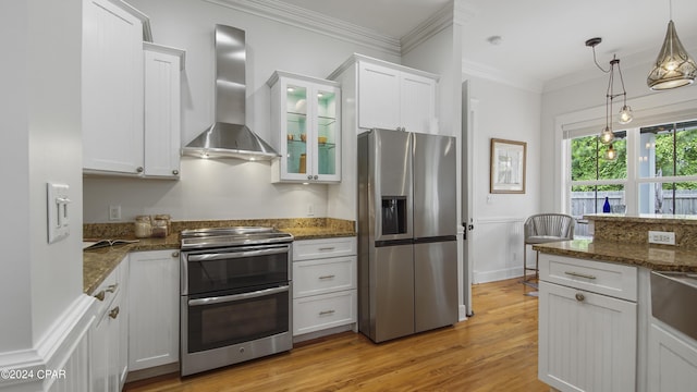 kitchen with white cabinets, appliances with stainless steel finishes, and wall chimney exhaust hood