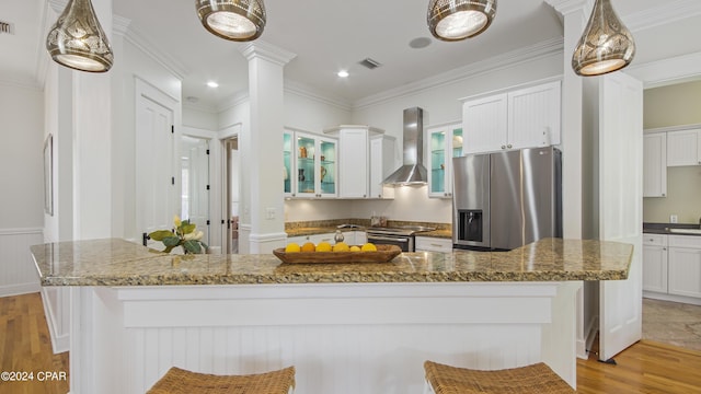 kitchen with a kitchen breakfast bar, appliances with stainless steel finishes, wall chimney range hood, and a large island