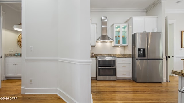 kitchen featuring white cabinetry, wall chimney range hood, stainless steel appliances, light wood-type flooring, and crown molding