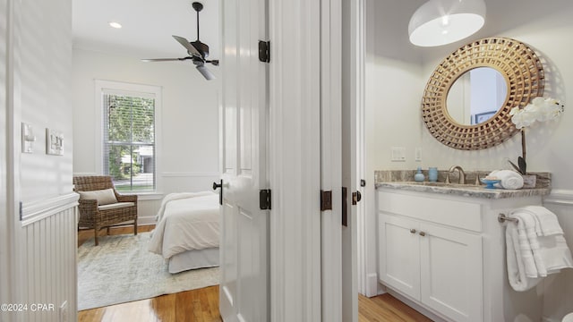 bathroom with ceiling fan, crown molding, wood-type flooring, and vanity