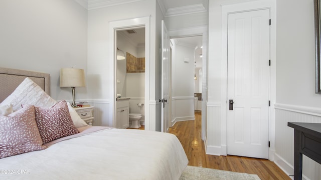 bedroom with ensuite bathroom, ornamental molding, and light hardwood / wood-style floors