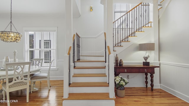 staircase featuring hardwood / wood-style flooring, ornamental molding, and an inviting chandelier