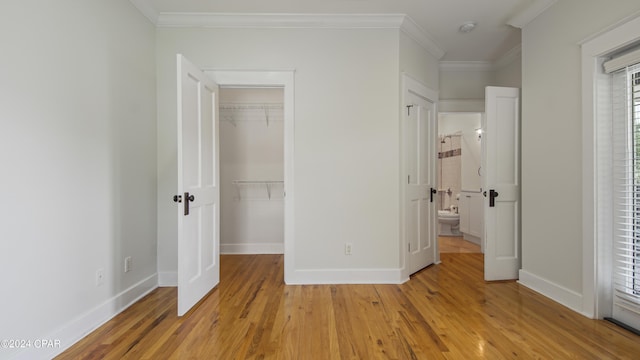 unfurnished bedroom featuring a closet, crown molding, multiple windows, and light hardwood / wood-style floors