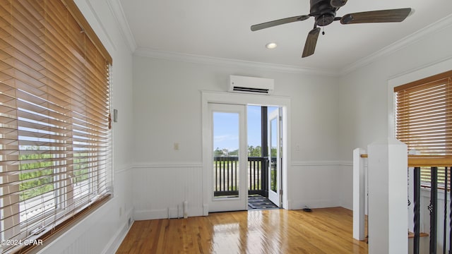 spare room with a wall unit AC, a healthy amount of sunlight, crown molding, and light hardwood / wood-style floors