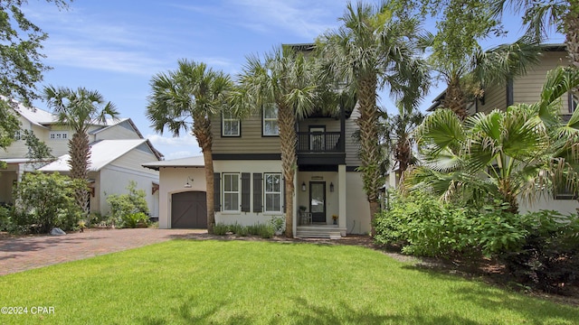 view of front of house with a garage, a front yard, and a balcony