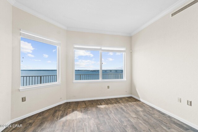 empty room featuring ornamental molding, a water view, and dark wood-type flooring