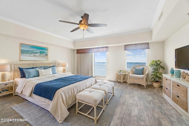 bedroom with ceiling fan, a textured ceiling, wood finished floors, visible vents, and crown molding