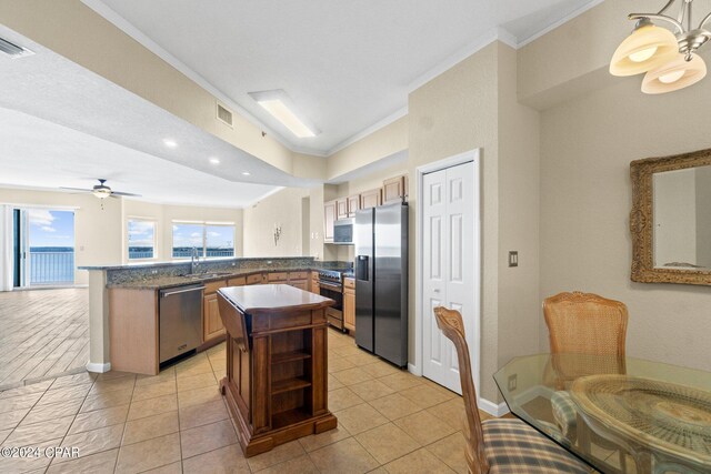 kitchen with a center island, crown molding, appliances with stainless steel finishes, light tile patterned flooring, and kitchen peninsula