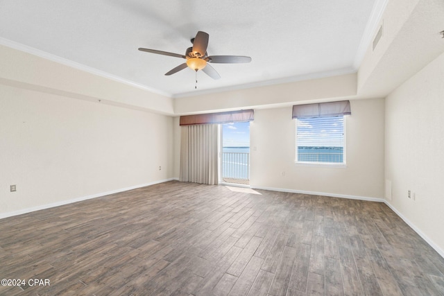 empty room with baseboards, visible vents, a ceiling fan, ornamental molding, and wood finished floors