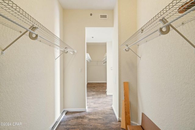 spacious closet featuring dark wood-type flooring and a baseboard heating unit