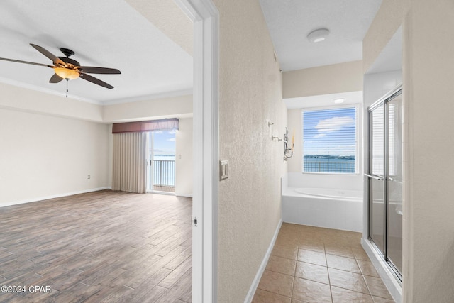 corridor featuring crown molding, a textured wall, light wood finished floors, and baseboards