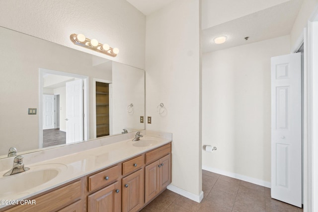 full bath featuring double vanity, tile patterned flooring, a sink, and baseboards