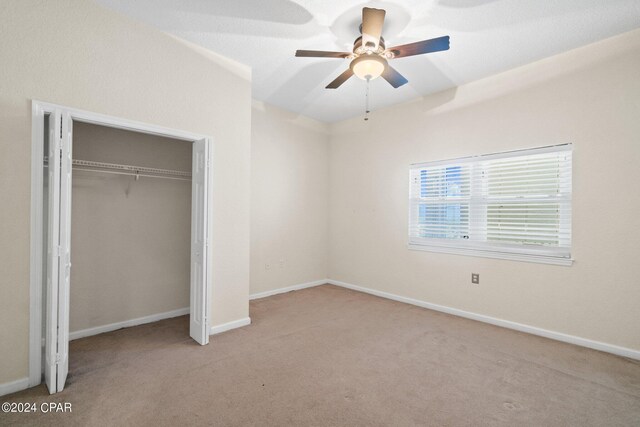 unfurnished bedroom featuring light carpet, a closet, and ceiling fan