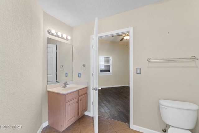 bathroom featuring hardwood / wood-style floors, vanity, ceiling fan, toilet, and a textured ceiling