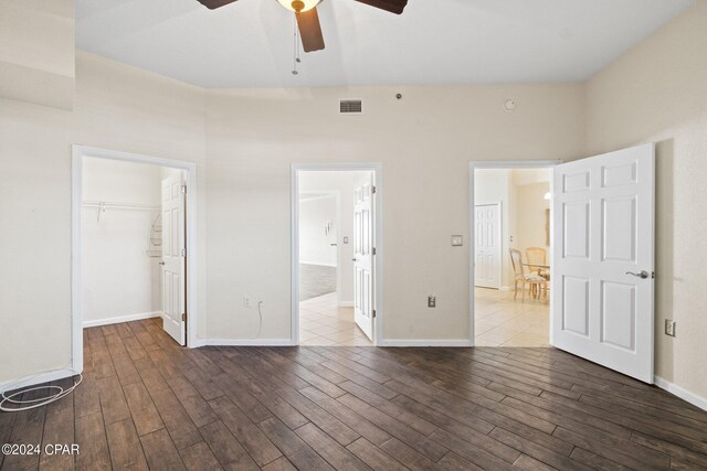 unfurnished bedroom featuring a closet, dark hardwood / wood-style floors, a spacious closet, and ceiling fan