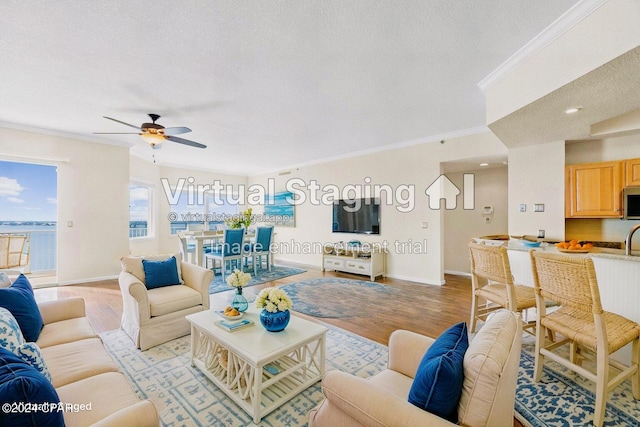 living room featuring ceiling fan, crown molding, a textured ceiling, and light hardwood / wood-style flooring