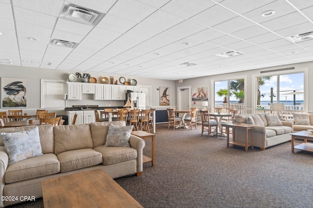 carpeted living room featuring a paneled ceiling and sink