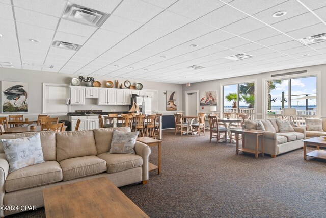 living area with dark colored carpet, a paneled ceiling, and visible vents