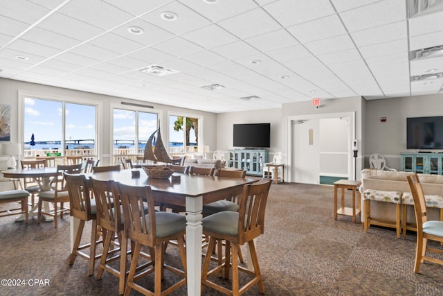 carpeted dining space with a drop ceiling and visible vents