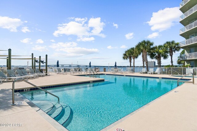 view of swimming pool with a water view and a patio