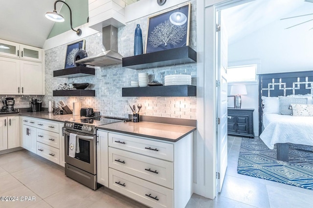 kitchen with tasteful backsplash, white cabinetry, lofted ceiling, wall chimney range hood, and electric stove