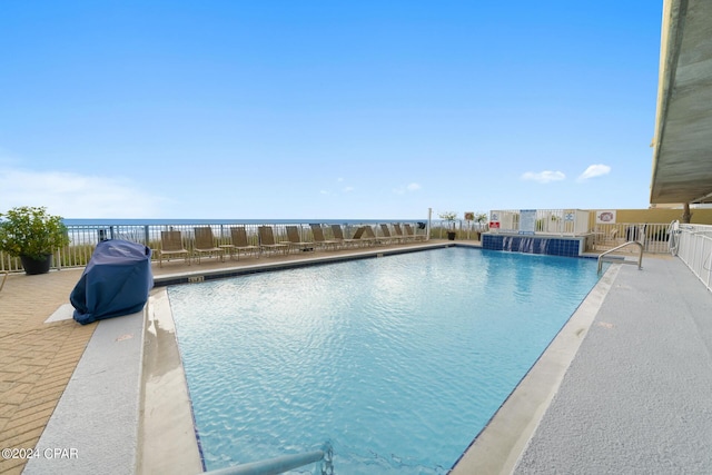 view of pool with pool water feature, a water view, and a patio