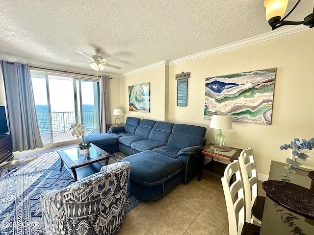 tiled living room with ceiling fan, a water view, ornamental molding, and a textured ceiling