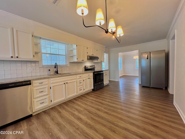 kitchen with light stone countertops, appliances with stainless steel finishes, hardwood / wood-style flooring, pendant lighting, and sink