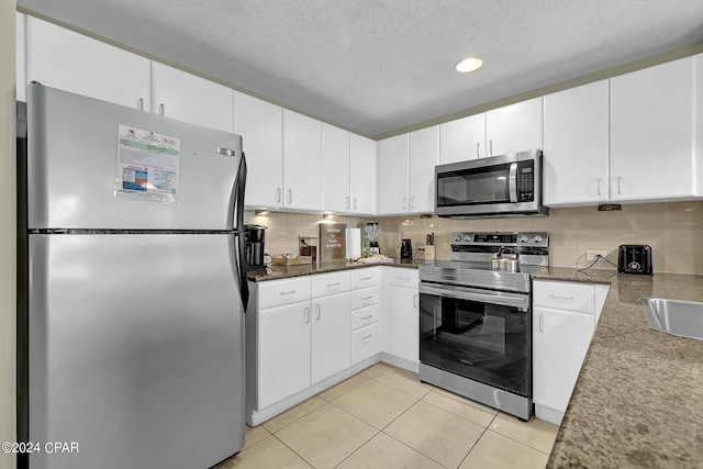 kitchen featuring appliances with stainless steel finishes, dark countertops, decorative backsplash, and white cabinets