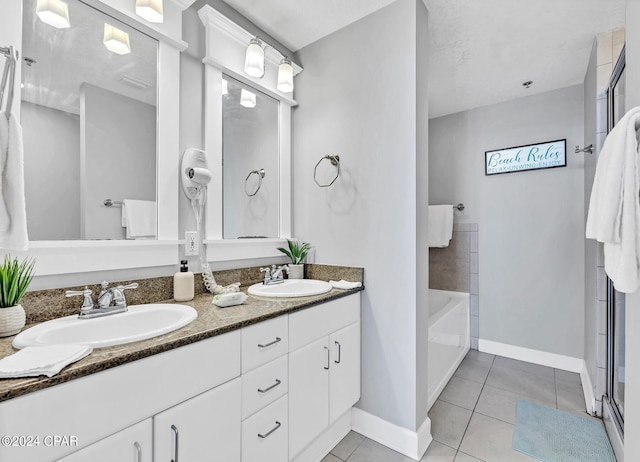 bathroom with double vanity, a bath, a sink, and tile patterned floors