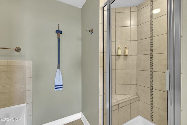 full bathroom with a washtub, baseboards, and tiled shower