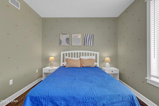 bedroom featuring dark wood finished floors, visible vents, and baseboards