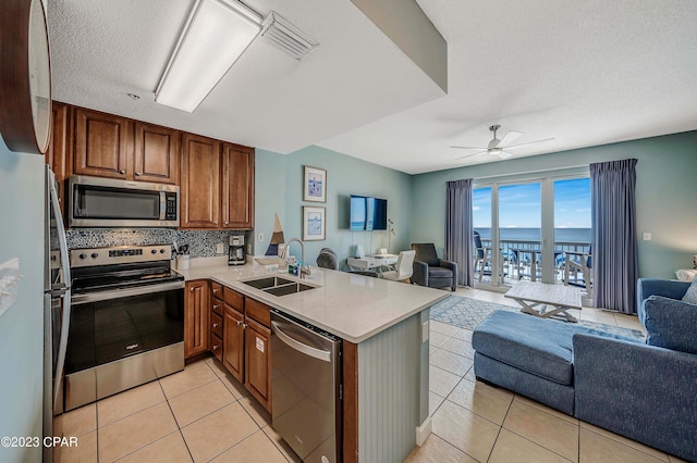 kitchen featuring sink, light tile patterned floors, ceiling fan, kitchen peninsula, and stainless steel appliances