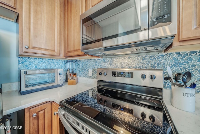 kitchen featuring stainless steel appliances, light stone countertops, and backsplash