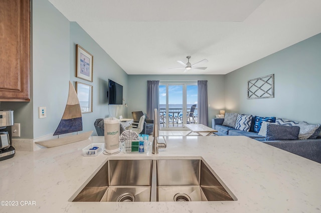 kitchen with light stone countertops, sink, and ceiling fan