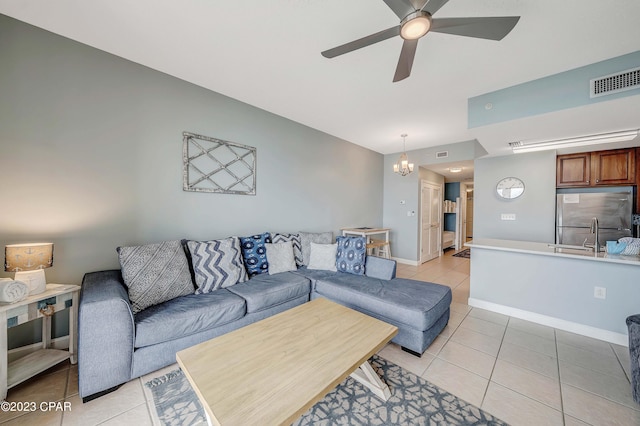 tiled living room featuring ceiling fan with notable chandelier